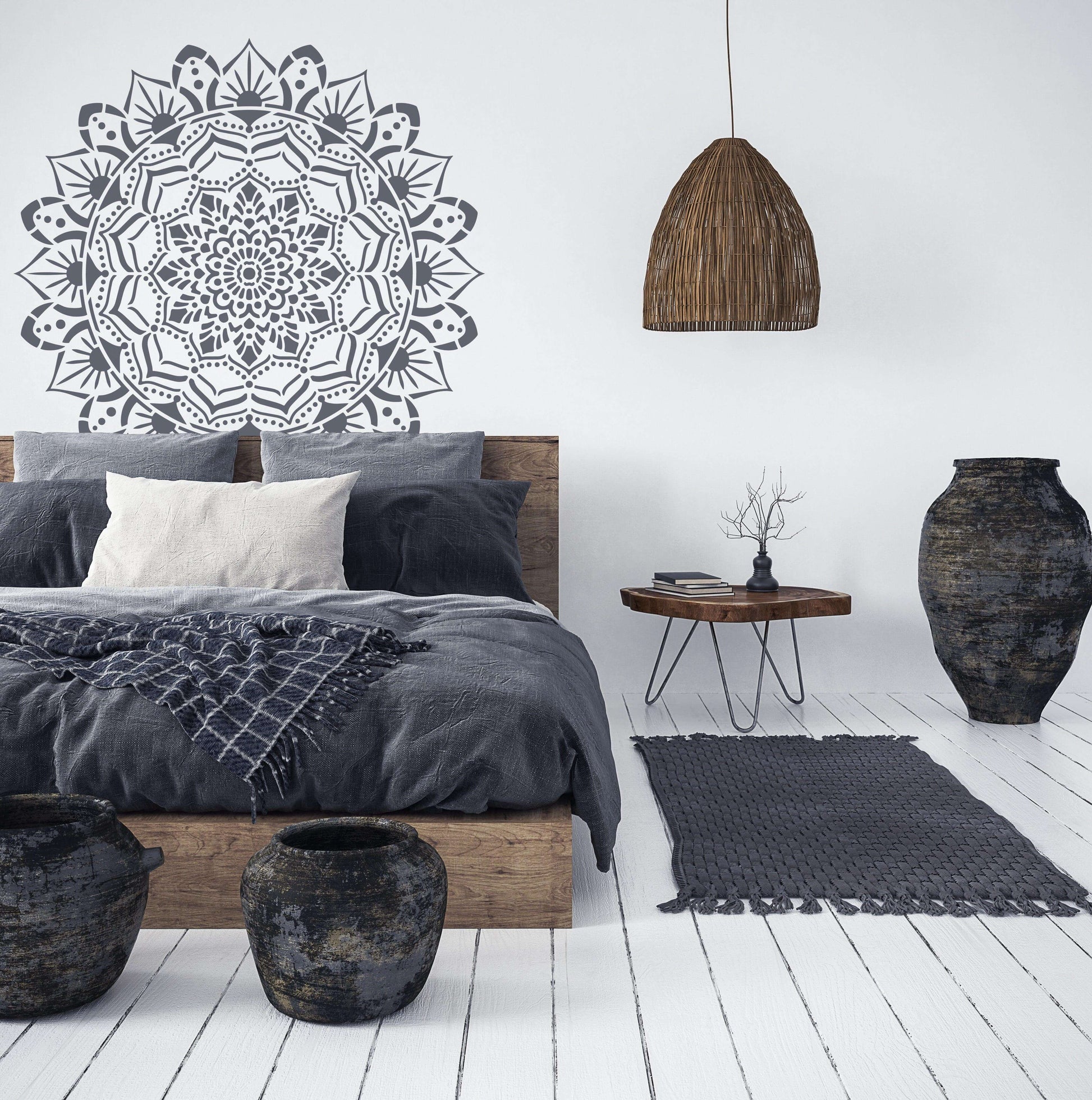 Large black and white mandala wall stencil above wooden bed with gray bedding in minimalist room.
