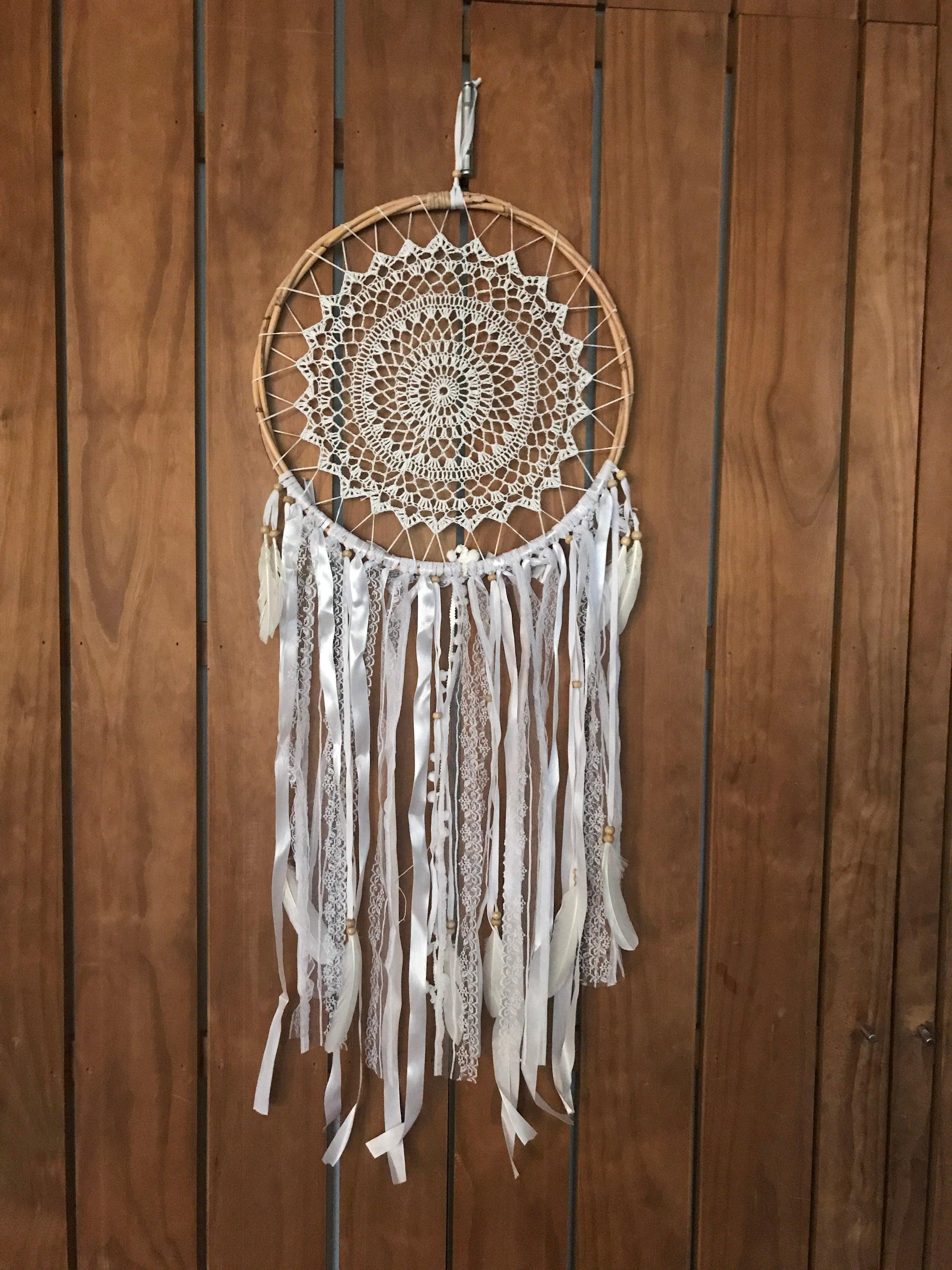 White handmade dream catcher with intricate lace web and cascading ribbons, 52cm length.