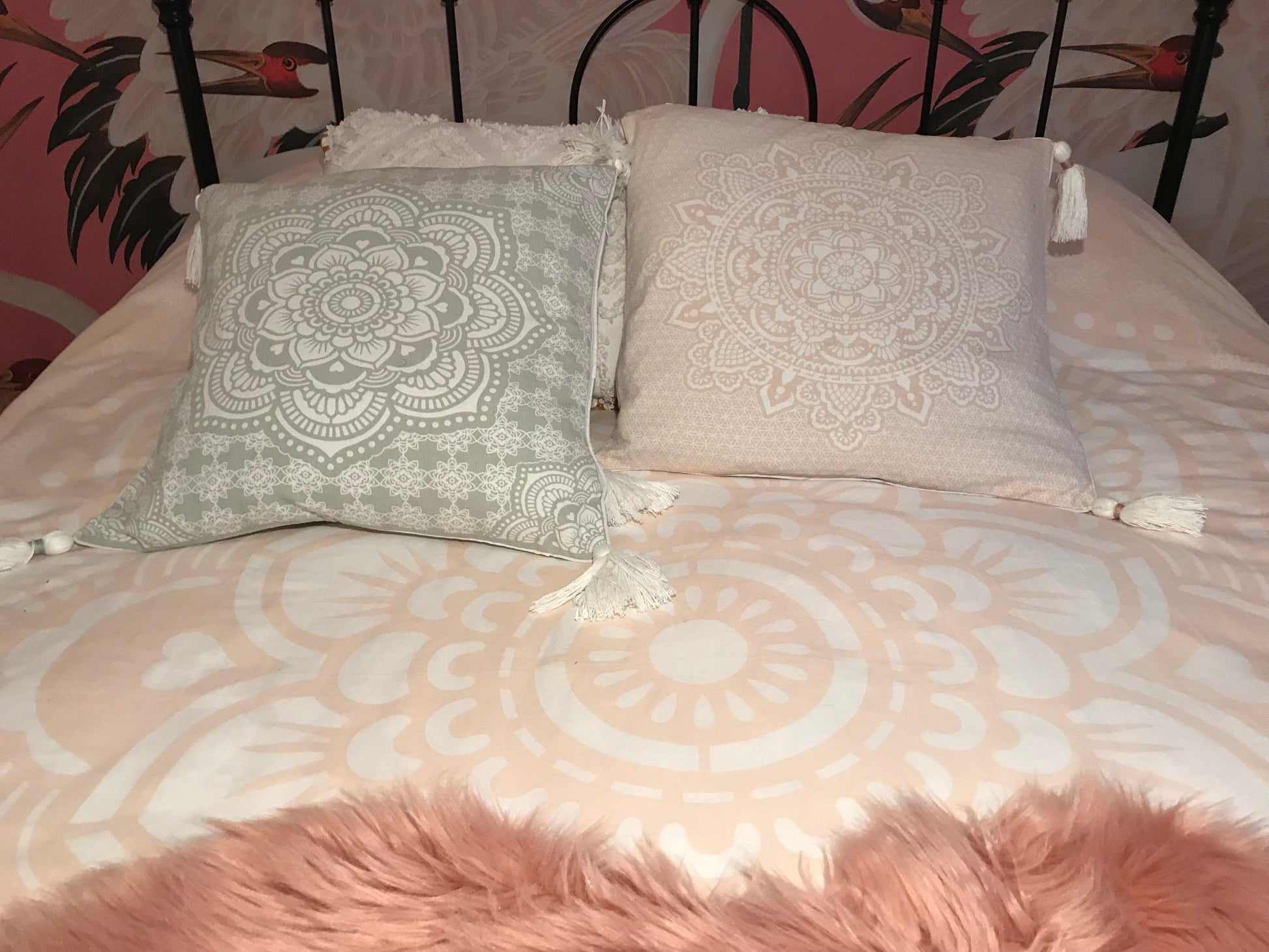 Square cushion with intricate white mandala print on soft pink fabric, 50x50 cm, tassels on corners.