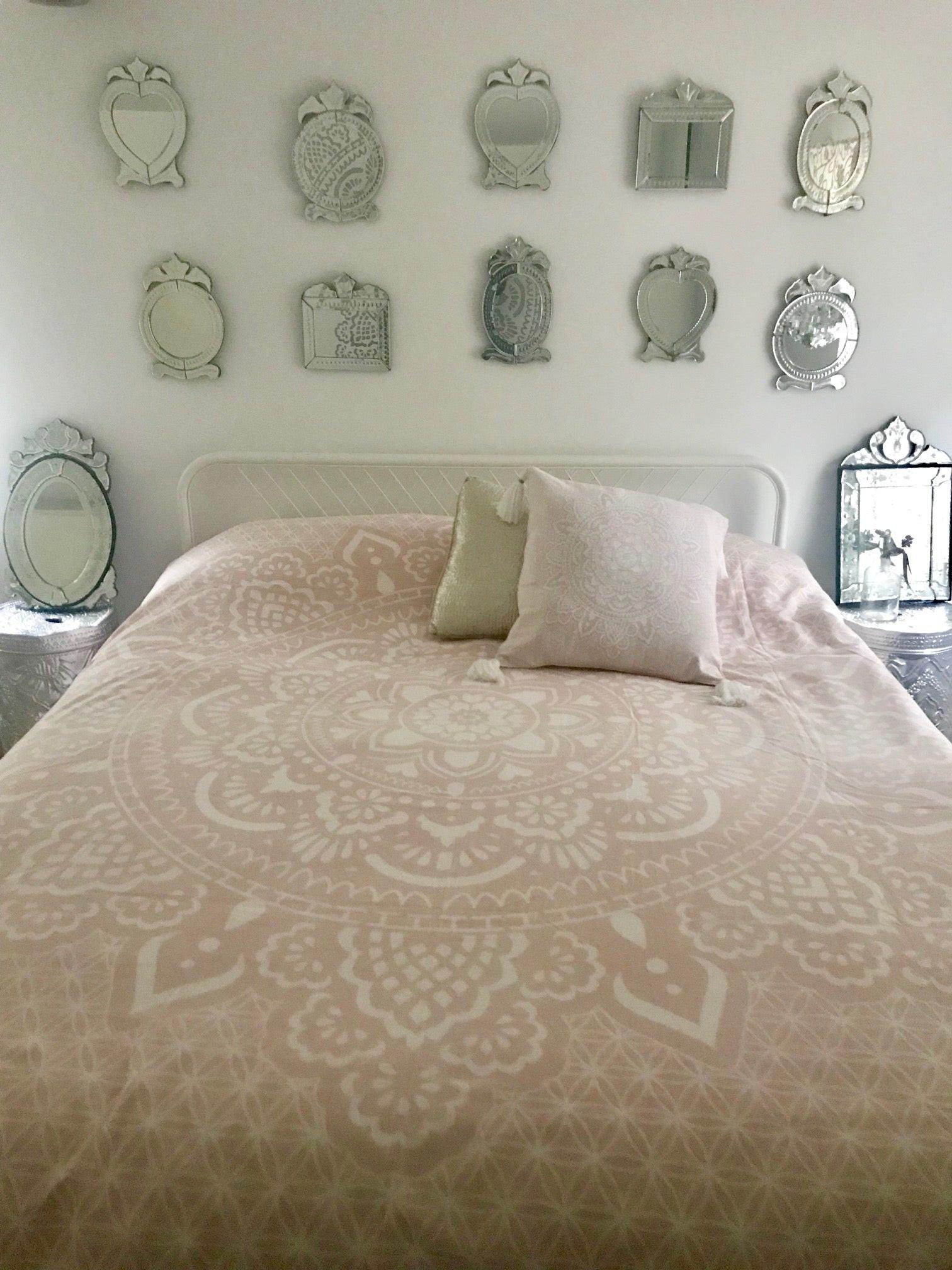 Soft pink bed cover with intricate white mandala pattern, paired with two matching pillows.