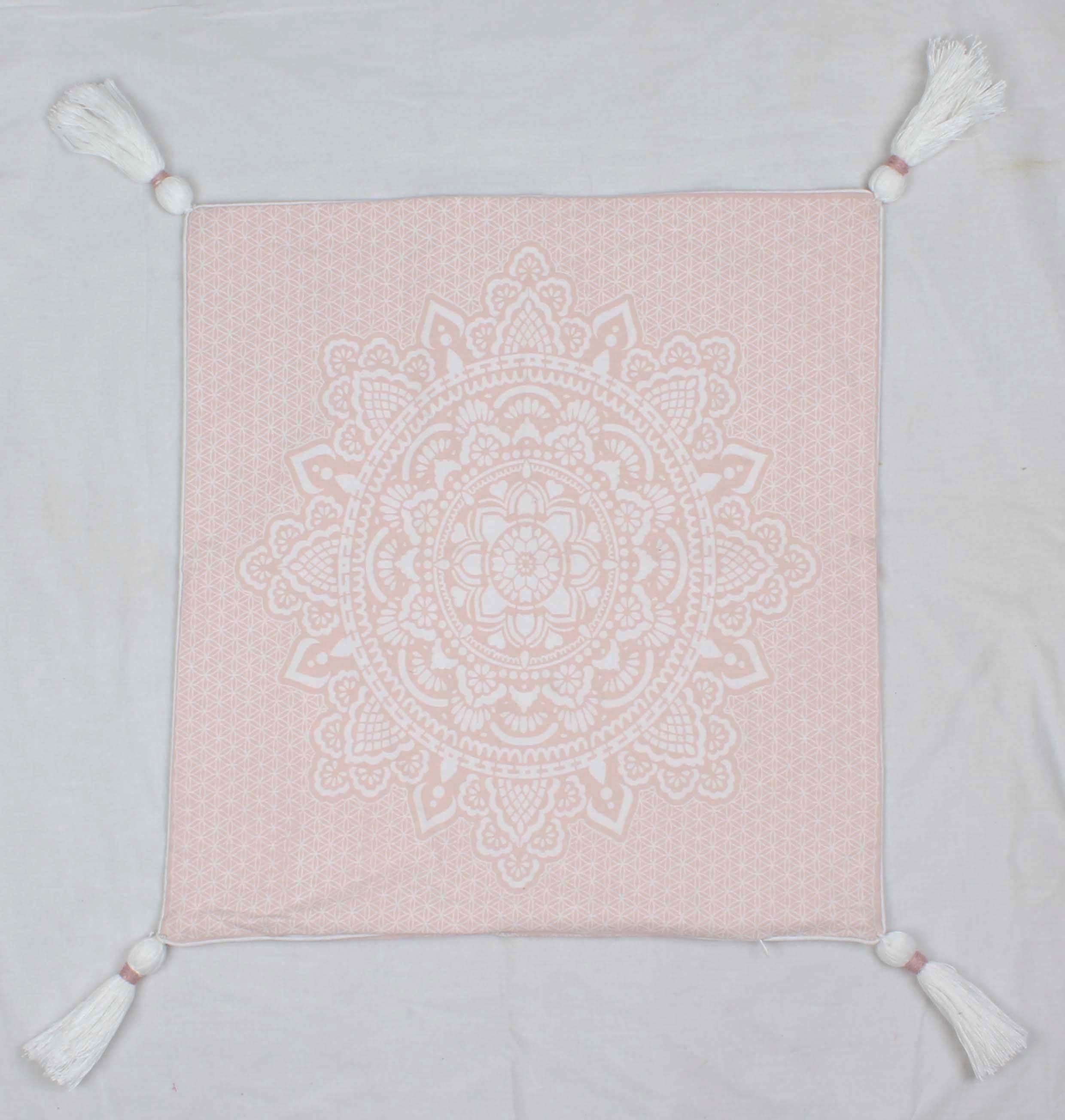 Square pink cushion cover with white intricate mandala print and tassels on each corner.