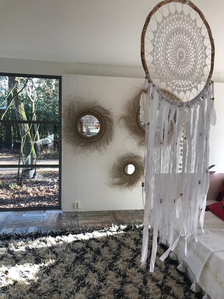 White crochet dream catcher with intricate web design, 42cm diameter, hanging above a textured rug.