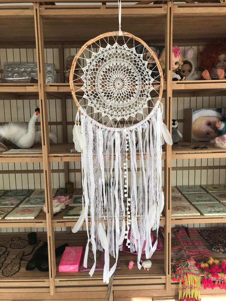 White crochet dreamcatcher with intricate circular pattern and long flowing fabric strips, 42cm diameter.